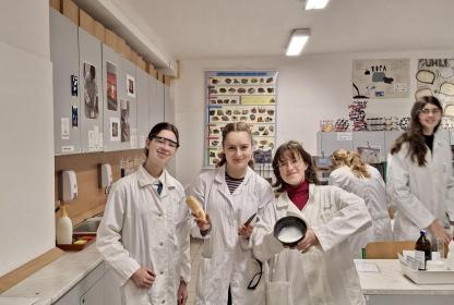Skupina studentek v laboratorních pláštích v chemické učebně