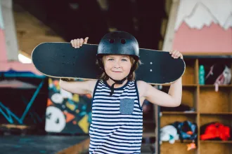 Chlapec v helmě drží nad hlavou skateboard